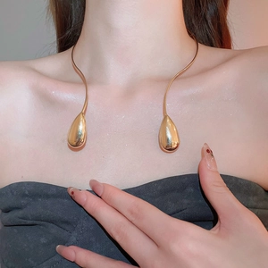Close-up of a gold metal choker necklace featuring elegant teardrop pendants on a model
