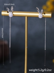 Detailed macro view of silver tassel earrings with bunny ear pearl studs and dimensions