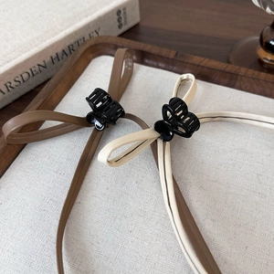 Detail of coffee and beige leather bow hair claws on a rustic wooden tray and linen cloth