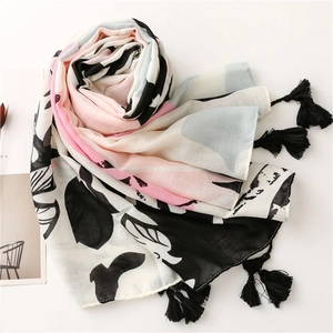 Detail of tropical floral print scarf featuring black fringe tassels on light fabric