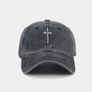 Close-up of white PEACE letter embroidery on dark grey washed cotton baseball cap