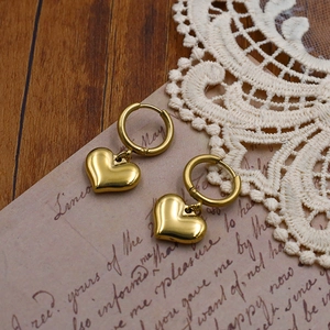 Chic gold-plated titanium steel heart drop earrings on vintage letter background