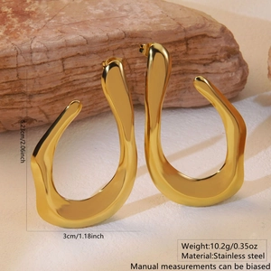 Macro shot of large golden irregular wavy hoop earrings with high polish stainless steel