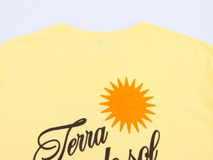 Dettaglio della maglietta in cotone giallo con scritta Terra la sol e grafica sole arancione