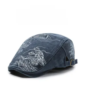 Macro shot of embroidered dragon pattern on washed denim flat cap with adjustable buckle