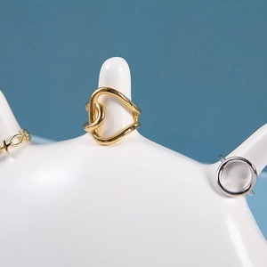Close-up of gold and silver geometric rings displayed on a white resin hand holder