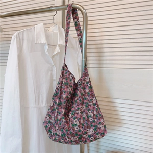 Detail of vintage navy blue floral hobo bag hanging on a rack with soft lighting