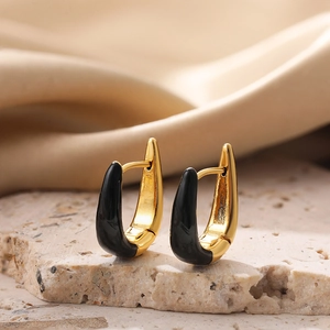 Detail of gold U-shaped earrings with black enamel on a textured stone base