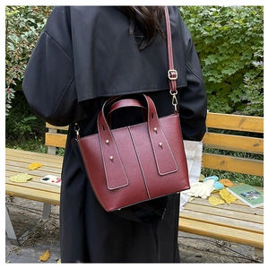 Détail du sac bandoulière en cuir bordeaux avec coutures blanches et finitions dorées