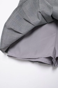 Détail de la jupe plissée à carreaux gris montrant la doublure short intégrée