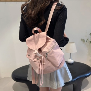 Rear view of pink nylon backpack featuring drawstring closure and stylish flap on model
