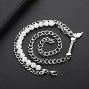 Detail of half-pearl half-chain necklace with wing and rod pendants on dark background