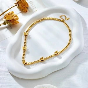 Elegant gold butterfly charm necklace with Cuban link chain on a decorative white tray