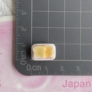 Miniature toast bread resin charm for DIY crafts shown on scale measuring 1.5cm