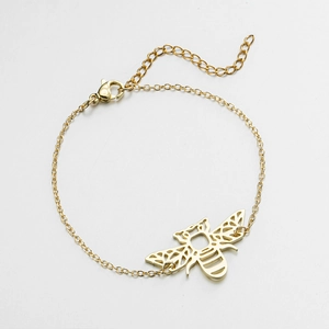 Macro detail of gold bee charm bracelet with hollow geometric wings and lobster clasp