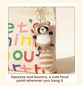 Detailed view of plush raccoon keychain with striped tail on a canvas bag