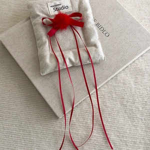 Detail of red ballet-style hair bow with plush pompom and long ribbons on beige decor
