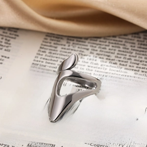 Macro view of a chunky silver geometric open knot ring on silk and vintage book