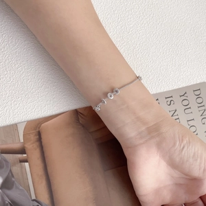 Detail of silver bead bracelet on wrist with textured rings and minimalist metal chain