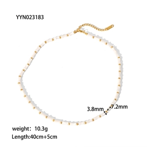 Macro shot of bamboo-shaped shell beads and gold-plated chain with lobster clasp detail