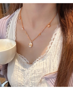Détail du collier en nacre ovale plaqué or 18K avec breloques étoiles sur un mannequin