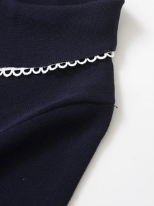 Macro shot of navy blue knit fabric with white wavy embroidered lace detailing