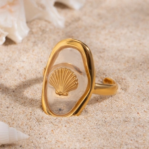 Detail of 18k gold plated stainless steel ring with shell design on beach sand
