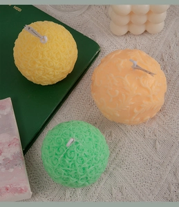 Detailed view of spherical rose carved scented candles in yellow, orange and green colors