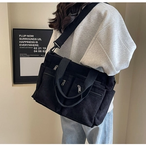 Action shot of model wearing a black corduroy tote bag with adjustable shoulder straps
