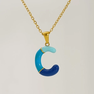 Macro view of blue enamel tricolor pendant necklace with golden letter C charm