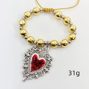 Detail view of heart charm bracelet with gold copper beads and red resin inlay