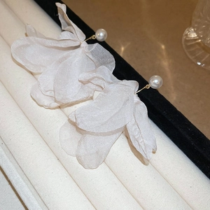 Detailed close-up of white fabric petal earrings with gold hooks and delicate pearls