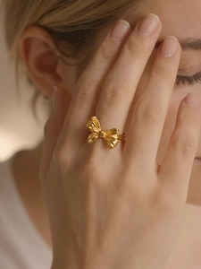 Detail of a 18K gold plated bow ring with delicate texture on a female index finger
