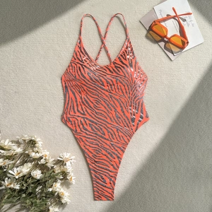 Detail of orange zebra print swimsuit with thin straps and gold foil on fabric texture