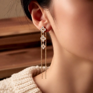 Close-up of elegant 18K gold-plated flower tassel earrings worn by a model in soft light