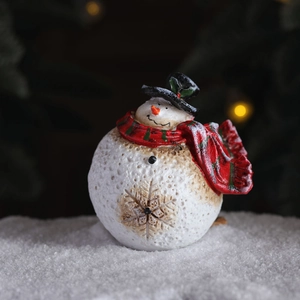 Festive resin snowman ornament with red plaid scarf on snow background