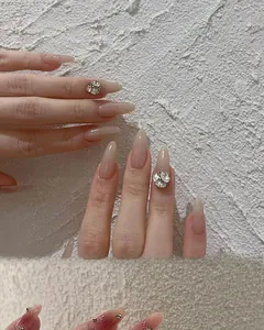 Détails d'ongles en amande dégradé rose nude avec accents de croix en cristal et paillettes