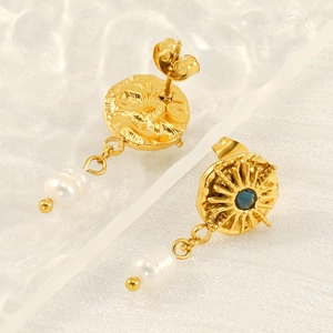 Detail of starburst earring featuring blue zircon center and white pearl drop charm