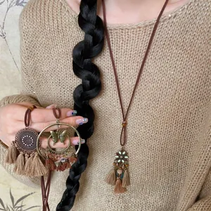 Detail of bohemian tassel necklaces featuring mandala and bow charms on brown wax cords