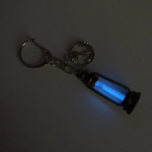 Close-up of a vintage kerosene lamp necklace pendant glowing in bright blue light