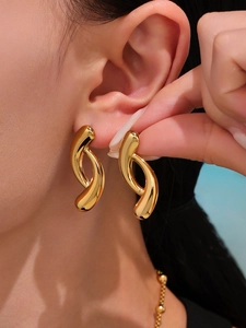 Detailed view of teardrop two-tone 18K gold earrings being worn for size contrast
