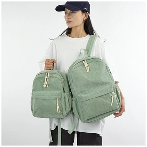 Comparison of mint green corduroy backpack sizes shown by model in professional studio