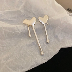 Detailed close-up of silver lava heart stud earrings on textured paper with natural lighting