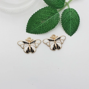 Detailed macro view of black and white butterfly charms with gold metal edges