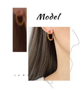 Detail of U-shaped gold-plated bamboo hoop earrings with natural texture on a model