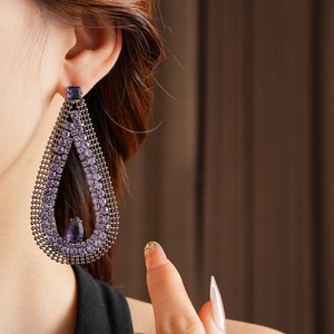 Close-up of vintage hollow purple teardrop earrings with crystals and mesh detail