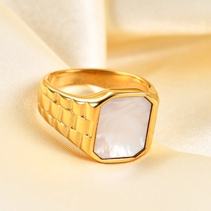 Macro detail of men's gold stainless steel ring with square mother of pearl on silk