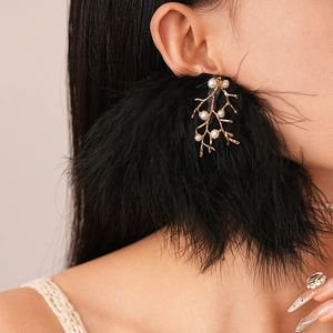 Gros plan détaillé de boucles d'oreilles plumes noires avec branches dorées et perles
