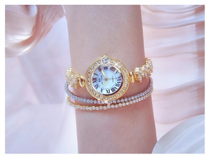 Close-up of gold quartz watch with diamond bezel and Roman numerals on woman's wrist