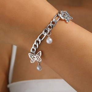 Detail of silver Cuban chain bracelet featuring hollow butterfly charm and white faux pearl